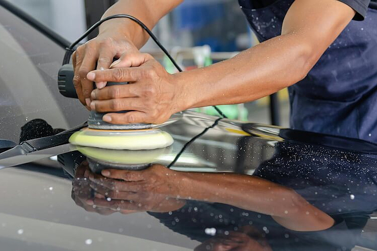 Ein Handwerker entfernt einen Autokratzer.