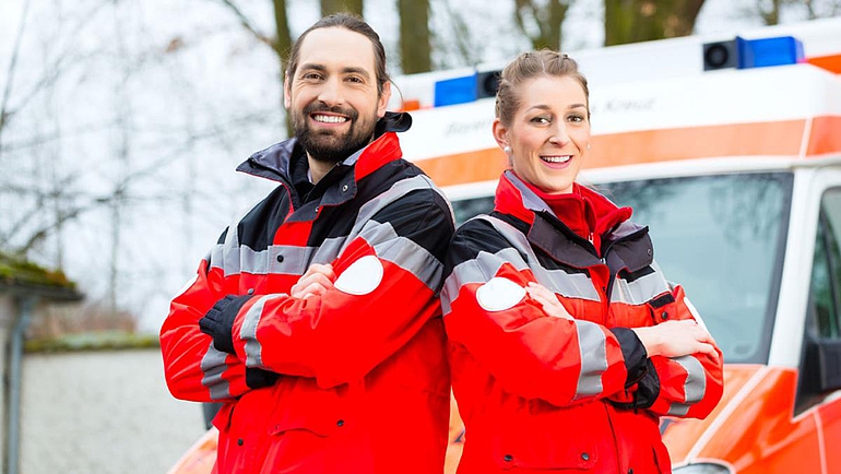 Notarzt und Sanitäter stehen vor einem Krankenwagen.