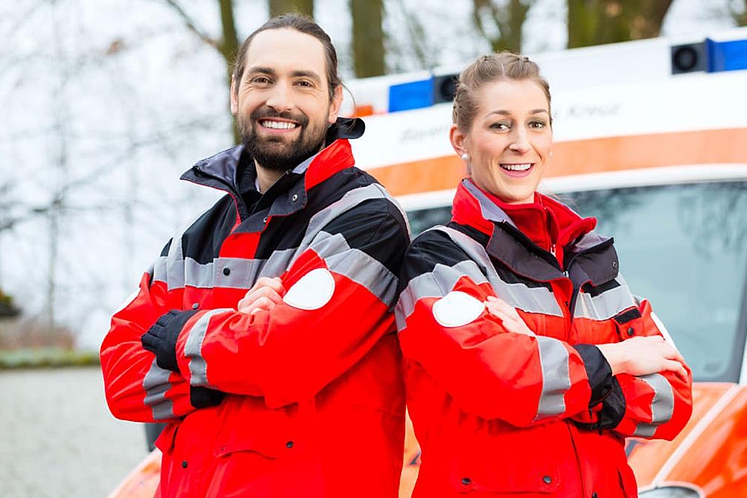 Notarzt und Sanitäter stehen vor einem Krankenwagen.