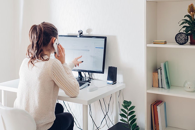 Eine freie Mitarbeiterin sitzt zuhause an ihrem Schreibtisch und arbeitet.