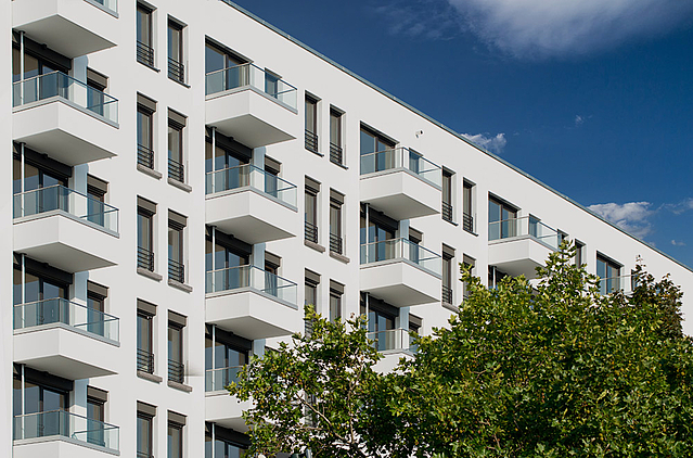 Auf dem Bild ist ein Wohnhaus mit vielen Balkonen zu sehen.